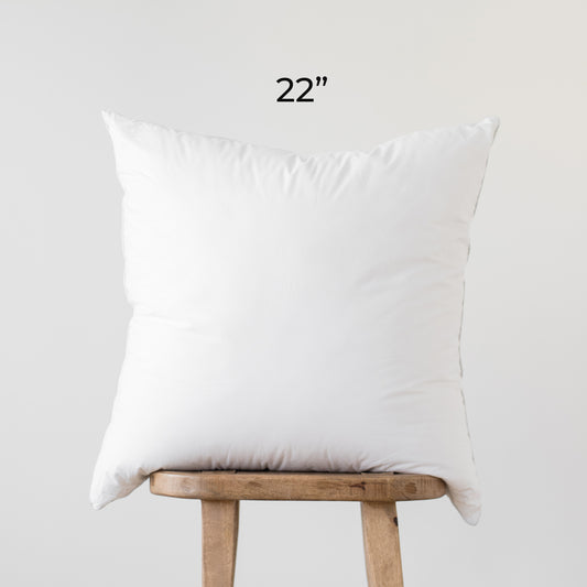 White square faux down pillow insert, 22 inches, displayed on wooden stand.