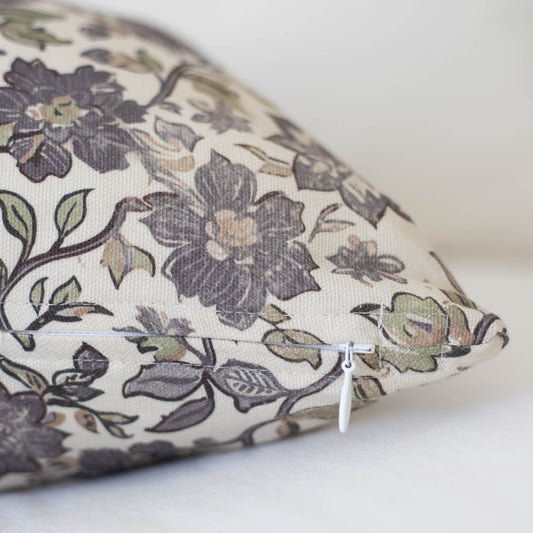 Cream pillow with dark gray and sage floral pattern, zipper closure visible on side.