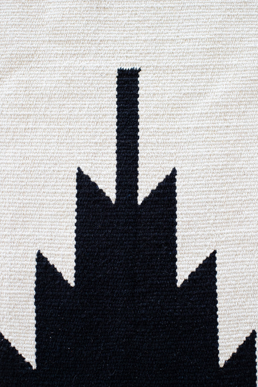 Cream and black woven rug with saguaro cactus silhouette design.