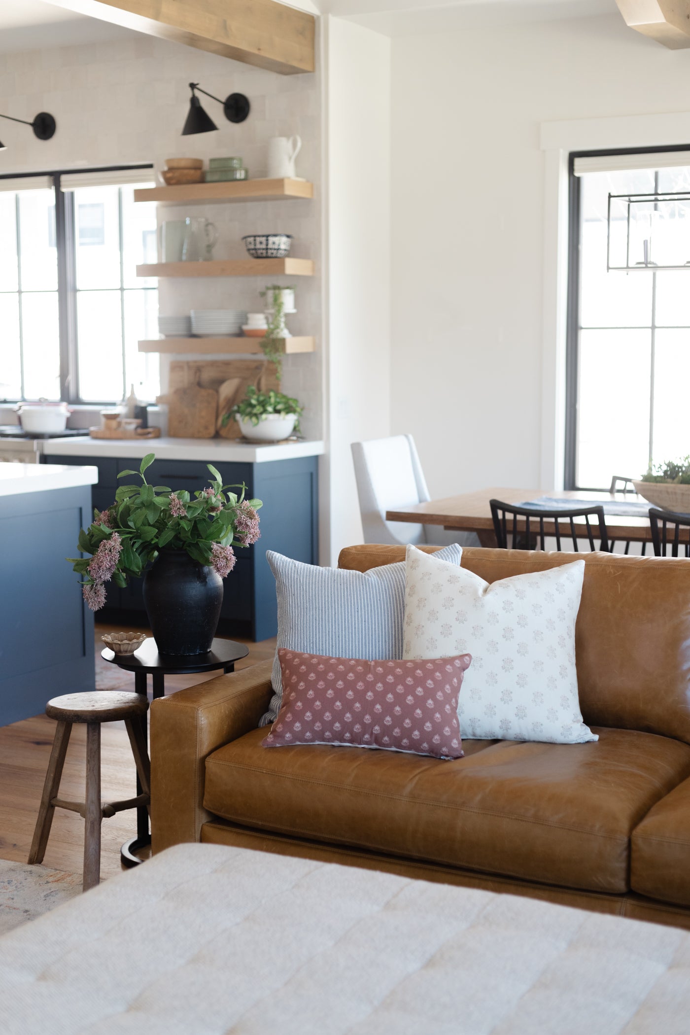 Clay-colored lumbar pillow with small dot pattern, displayed on tan leather sofa in living room setting.