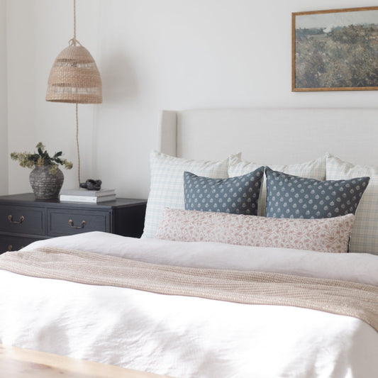 Woven pendant lamp with natural fibers hanging above a bedroom nightstand.