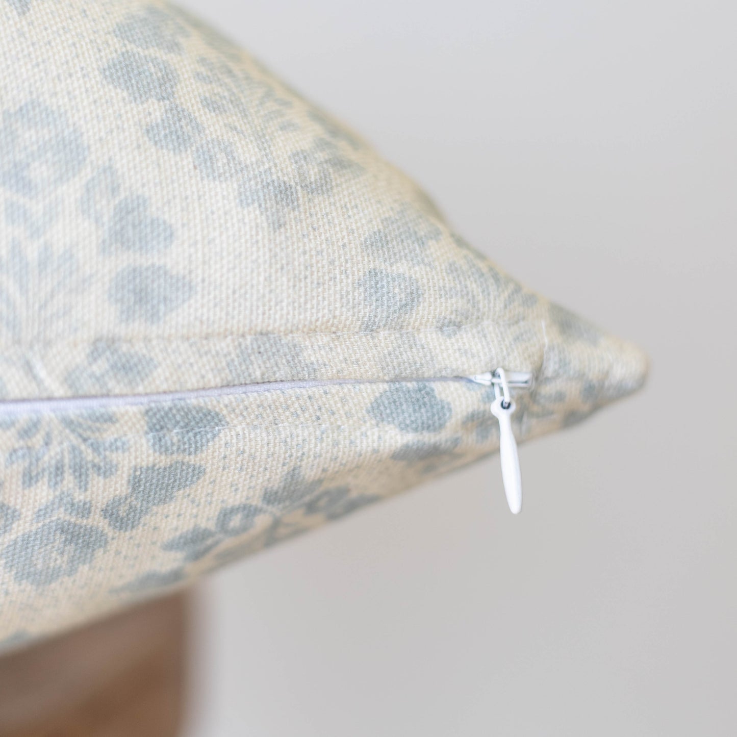 Cream and blue leopard print pillow with white zipper closure detail visible on seam.