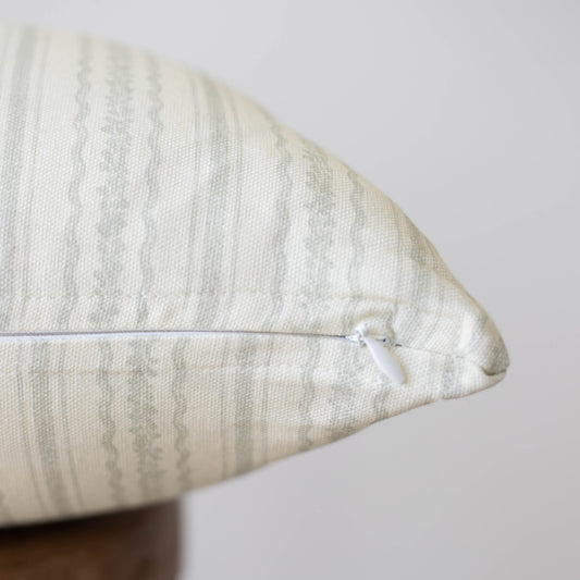 Cream textured pillow with geometric pattern and white zipper closure.