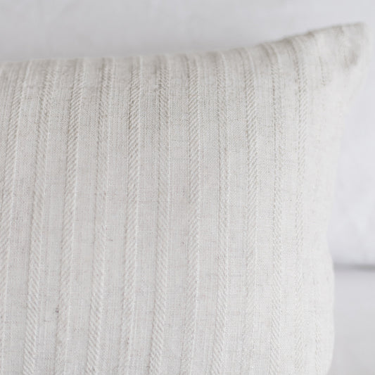 Cream-colored rectangular pillow with vertical cable knit texture pattern.
