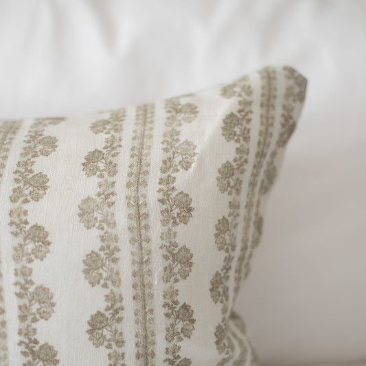 Cream linen pillow with vertical stripes of tan floral motifs and matching edge trim.