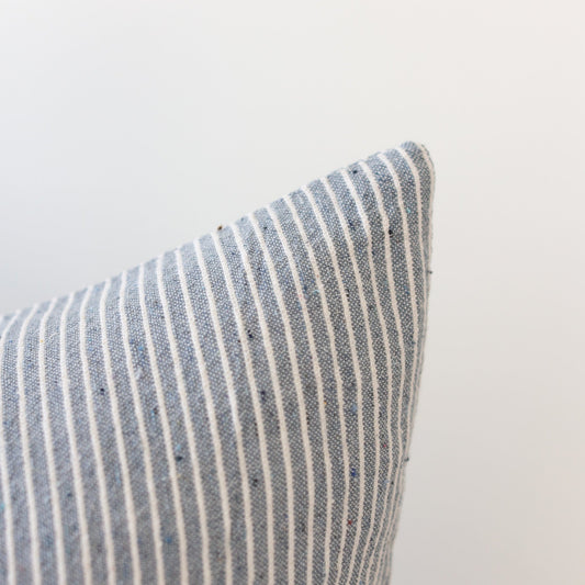 Blue and white striped pillow with textured woven fabric, shown at an angle against a neutral background.