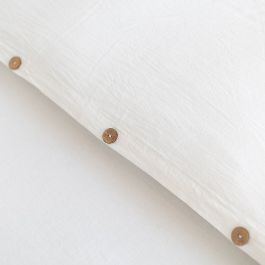 White duvet cover with wooden button closures along the edge.