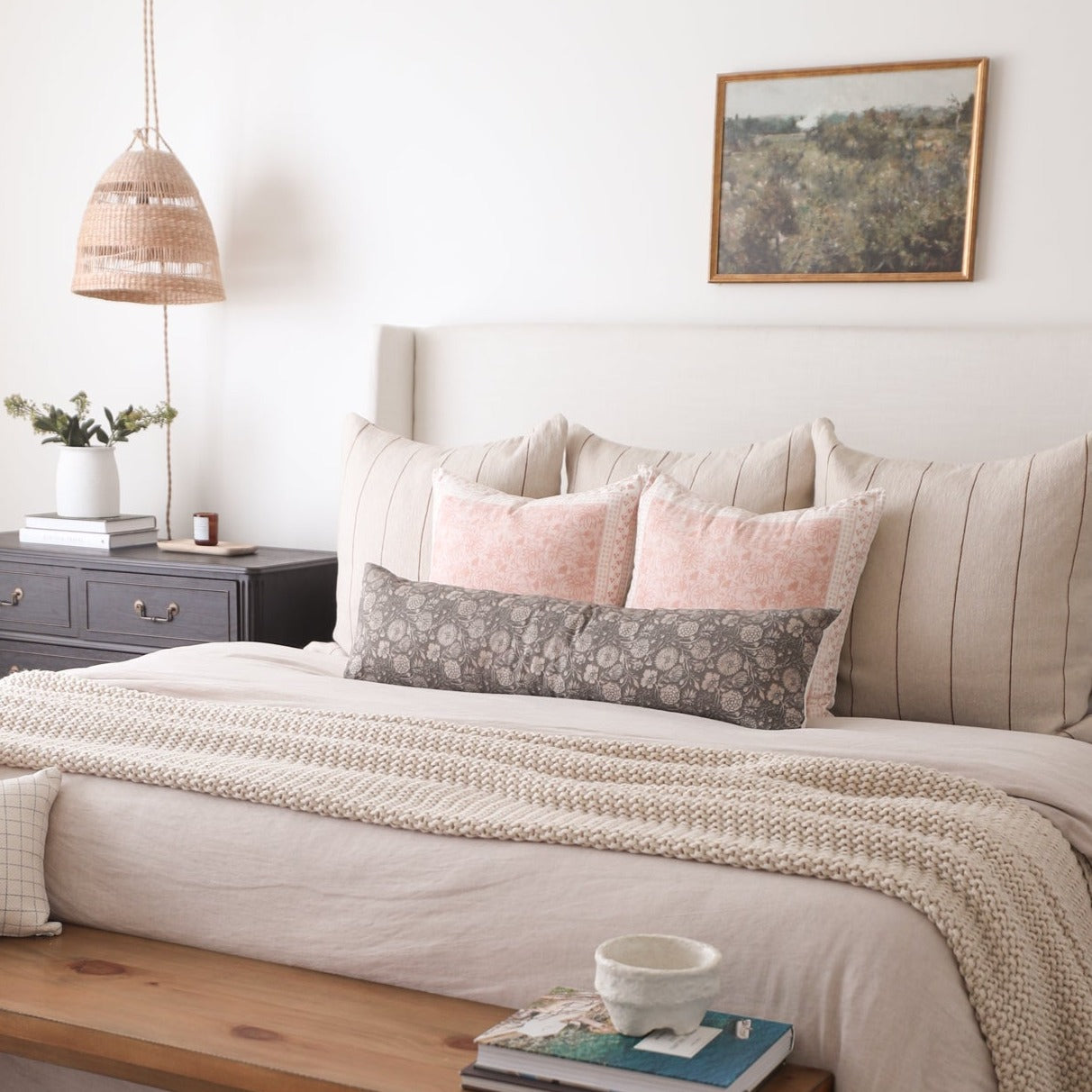 Rectangular lumbar pillow in pink with subtle texture pattern, displayed on a bed with other decorative pillows.