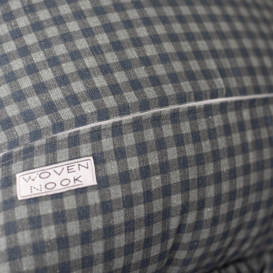 Navy and white gingham pillow with ruffle edge and brand label visible.