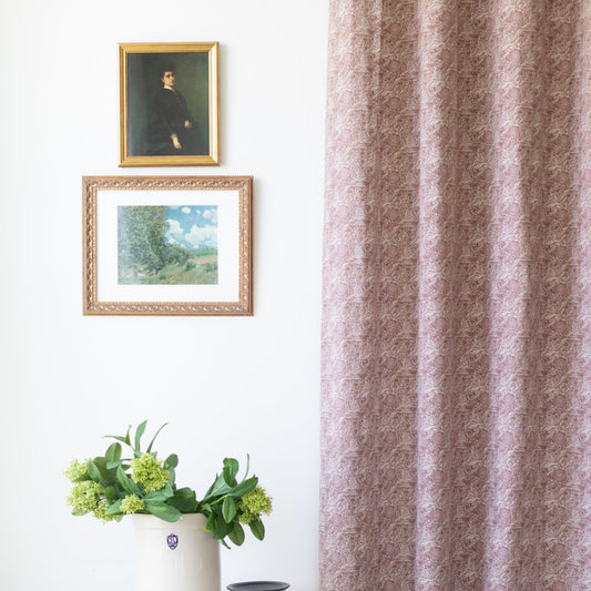Two mauve curtain panels with damask pattern hanging at window.