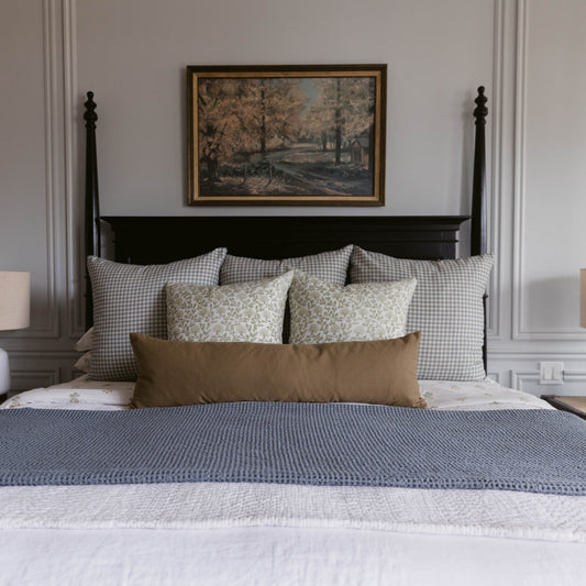 Moss Basics lumbar pillow in sage green displayed on bed with gingham and floral pillows.