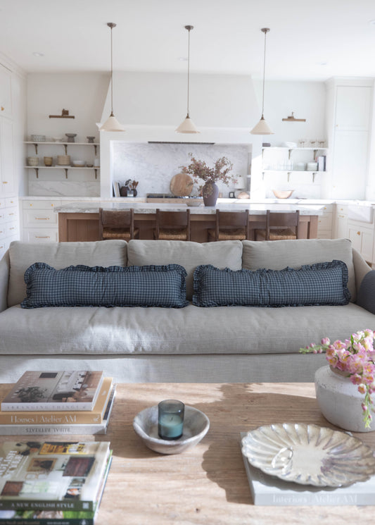 Navy gingham ruffle pillows with ruffled edges on gray sofa in living room.