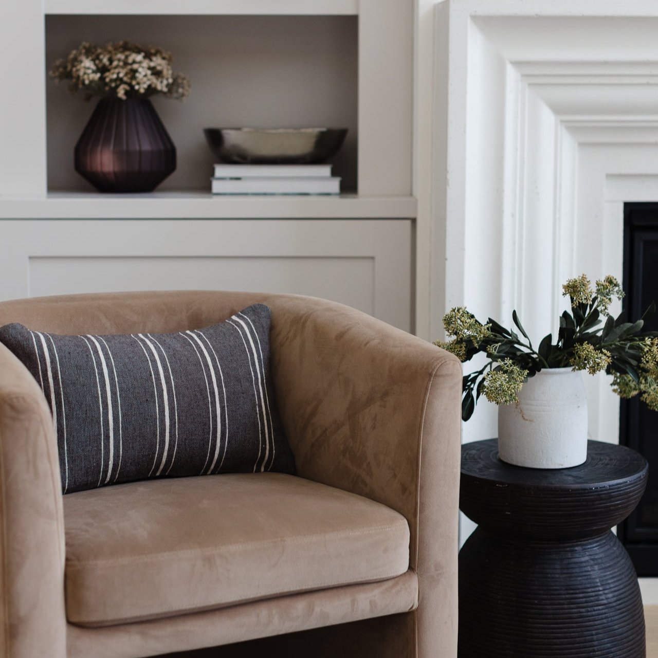 Charcoal lumbar pillow with white striped pattern on tan upholstered chair.