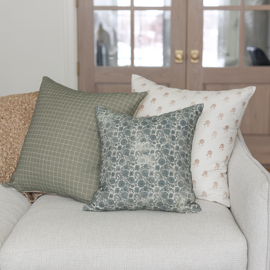 Moss green grid patterned pillow displayed on a cream sofa with coordinating pillows.