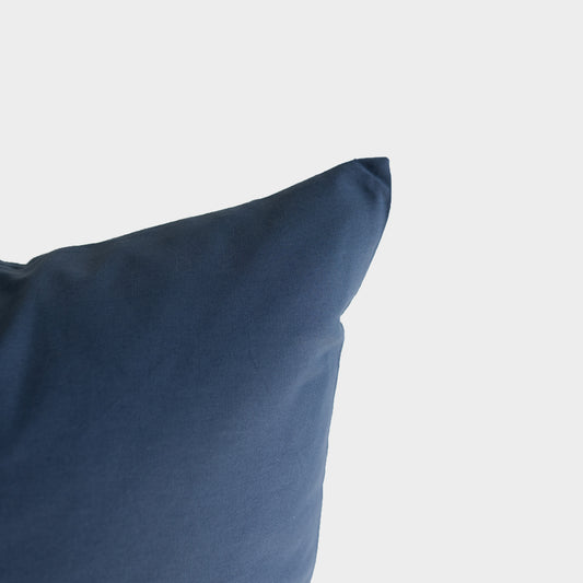 Navy blue pillow with soft fabric texture and rounded corner visible against white background.
