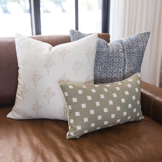Olive and white spaced check pillow displayed on brown leather sofa with coordinating pillows.