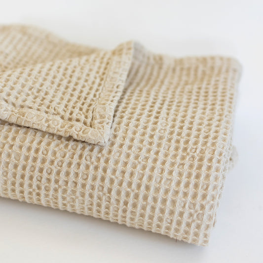 Ivory waffle-textured blanket folded with visible grid pattern weave.