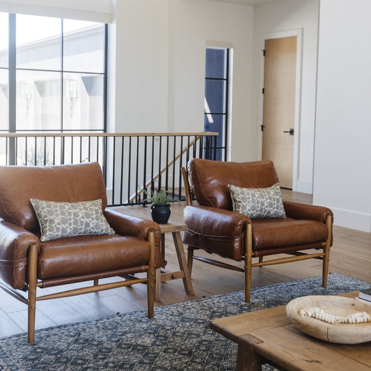 Beige geometric patterned lumbar pillow displayed on brown leather chair in living room setting.