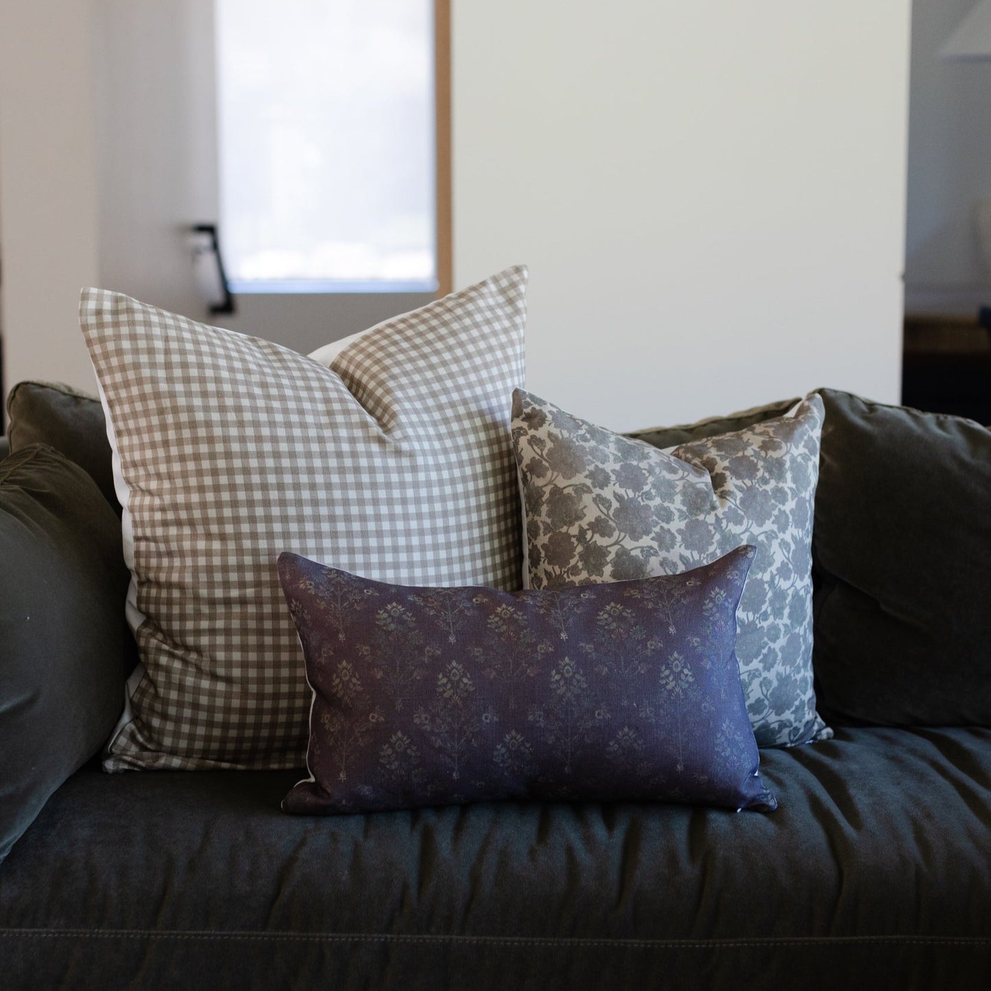 Dark burgundy linen lumbar pillow with tonal damask pattern displayed on black sofa.