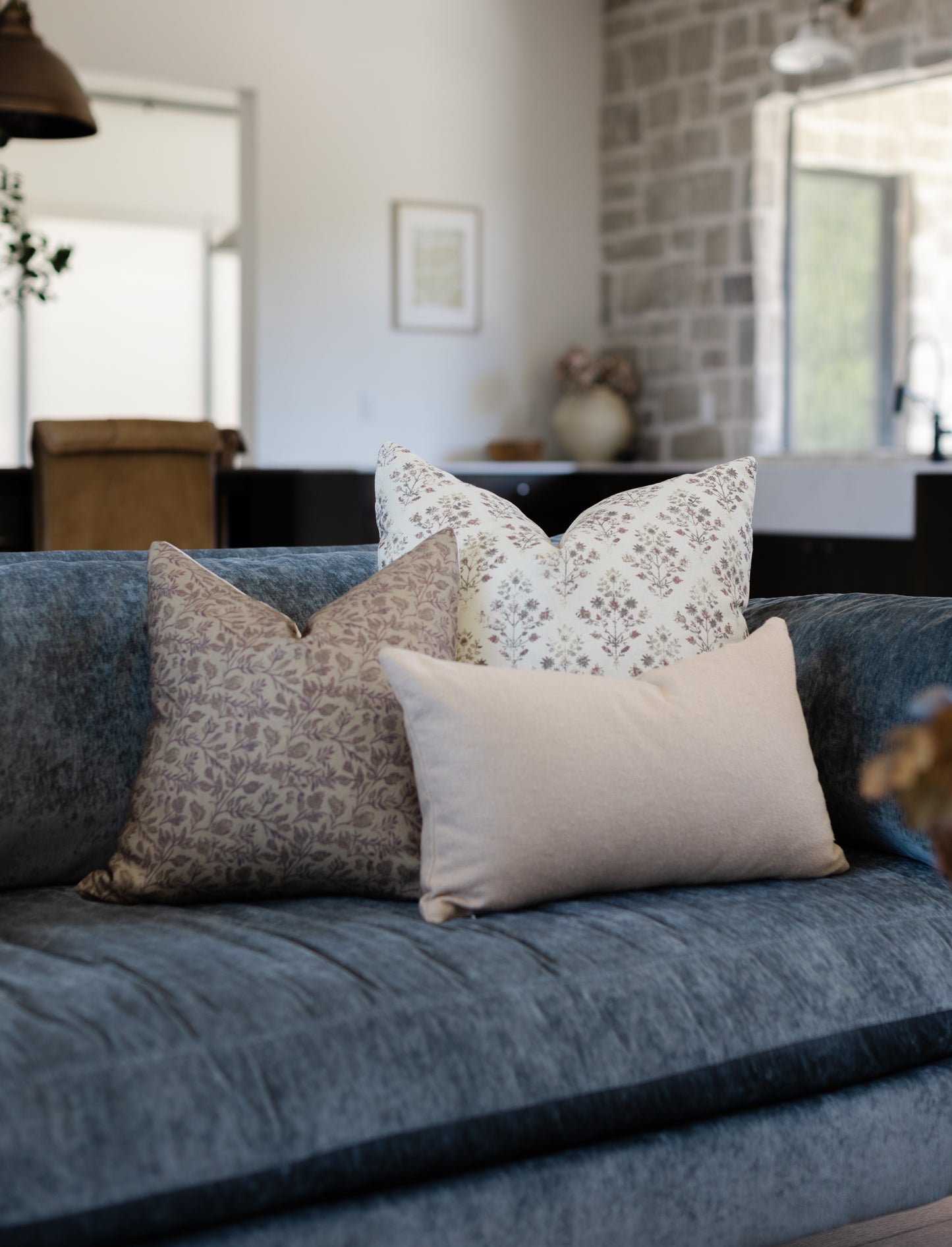 Beige boucle textured rectangular pillow displayed on a blue upholstered sofa with patterned and solid pillows.