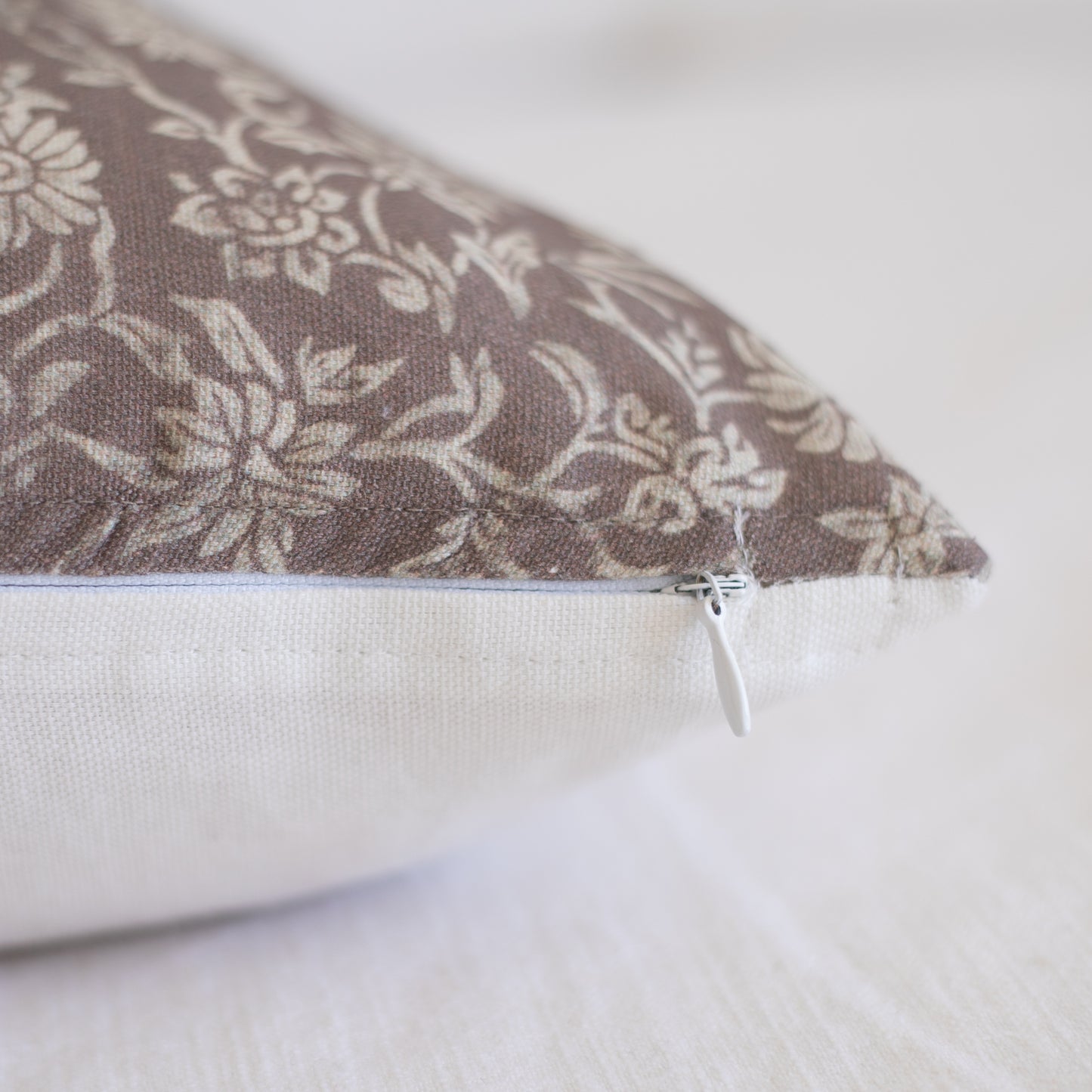 Rectangular lumbar pillow with taupe damask pattern on front and white zipper closure on side.