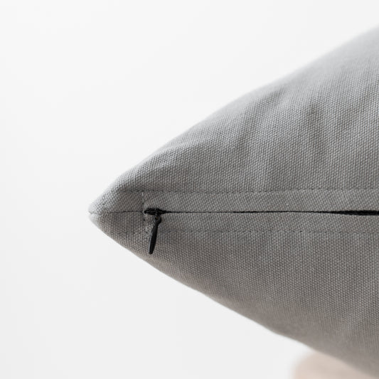 Gray textured pillow with concealed zipper closure, close-up detail view.
