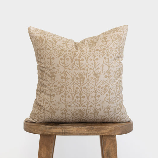 Beige pillow cover with tan floral and geometric pattern, displayed on wooden stool.