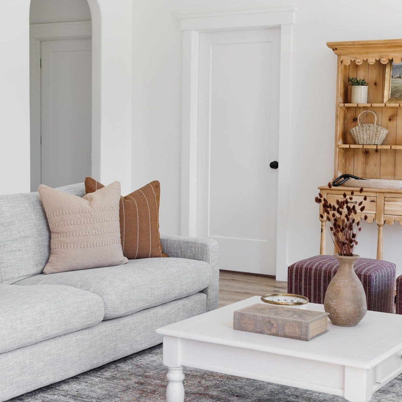 Tan striped lumbar pillow displayed on a gray upholstered sofa in a modern living room setting.