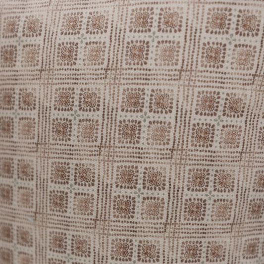 Brown and cream lumbar pillow with geometric grid pattern of textured floral squares.
