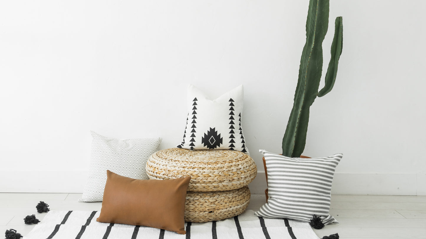 Milo lumbar pillow with white background, black triangle and diamond geometric pattern, displayed with decorative pillows and