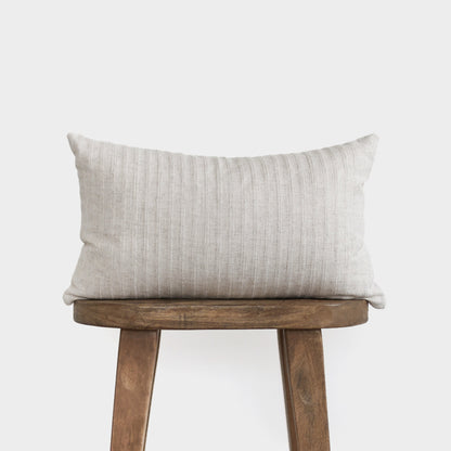 Cream ribbed rectangular pillow with vertical texture on wooden stool.