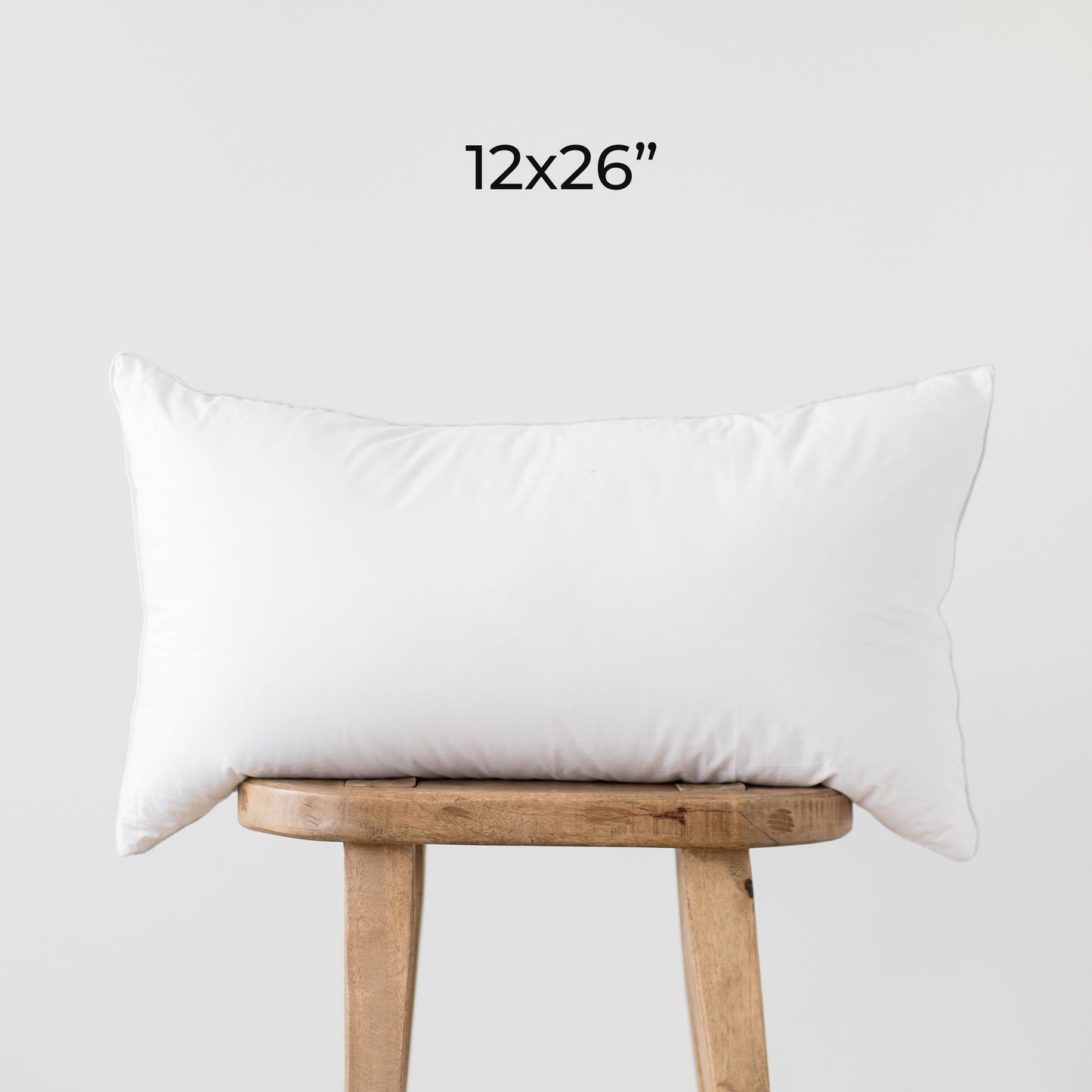 White rectangular faux down insert, 12x26 inches, displayed on wooden stool.