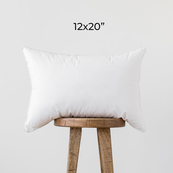 White rectangular faux down pillow insert, 12x20", displayed on wooden stool.