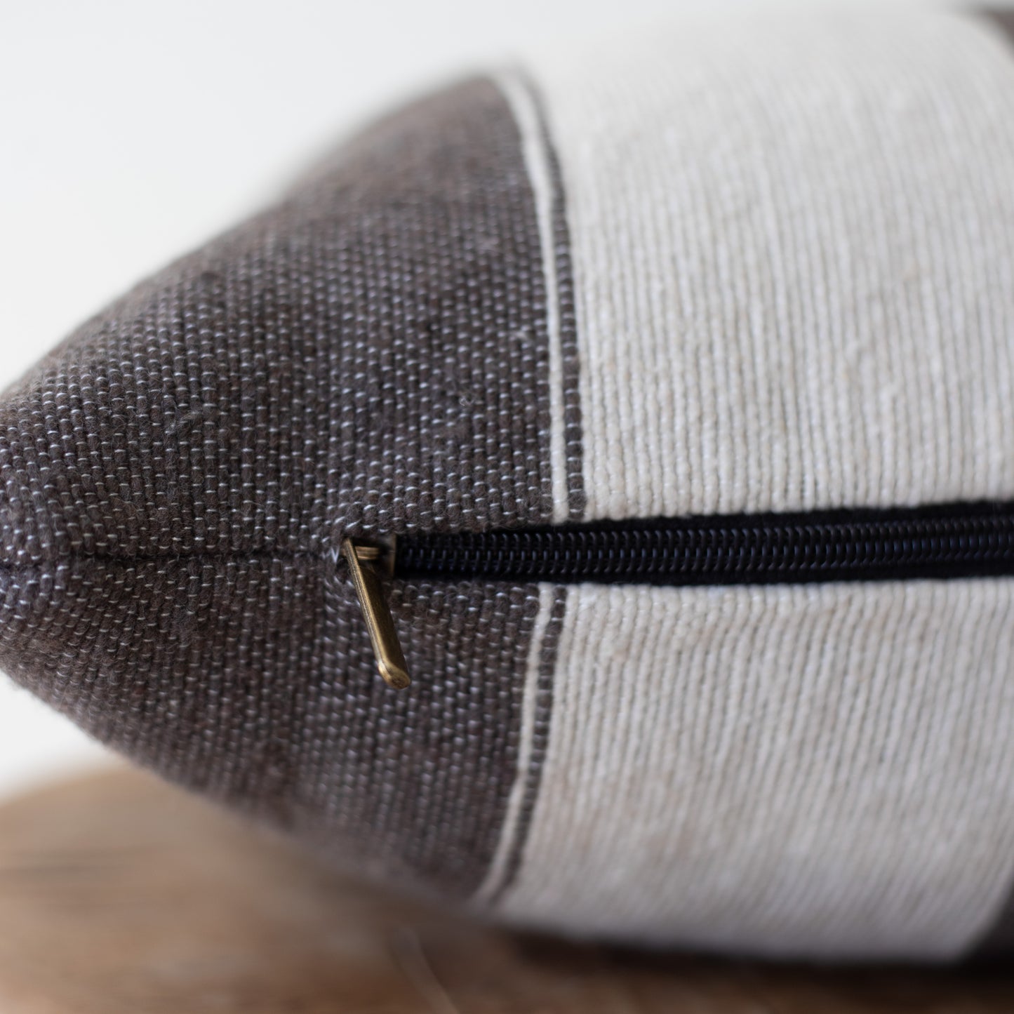 Cylindrical lumbar pillow with dark gray textured fabric on one side, light gray ribbed fabric on the other, and black zipper