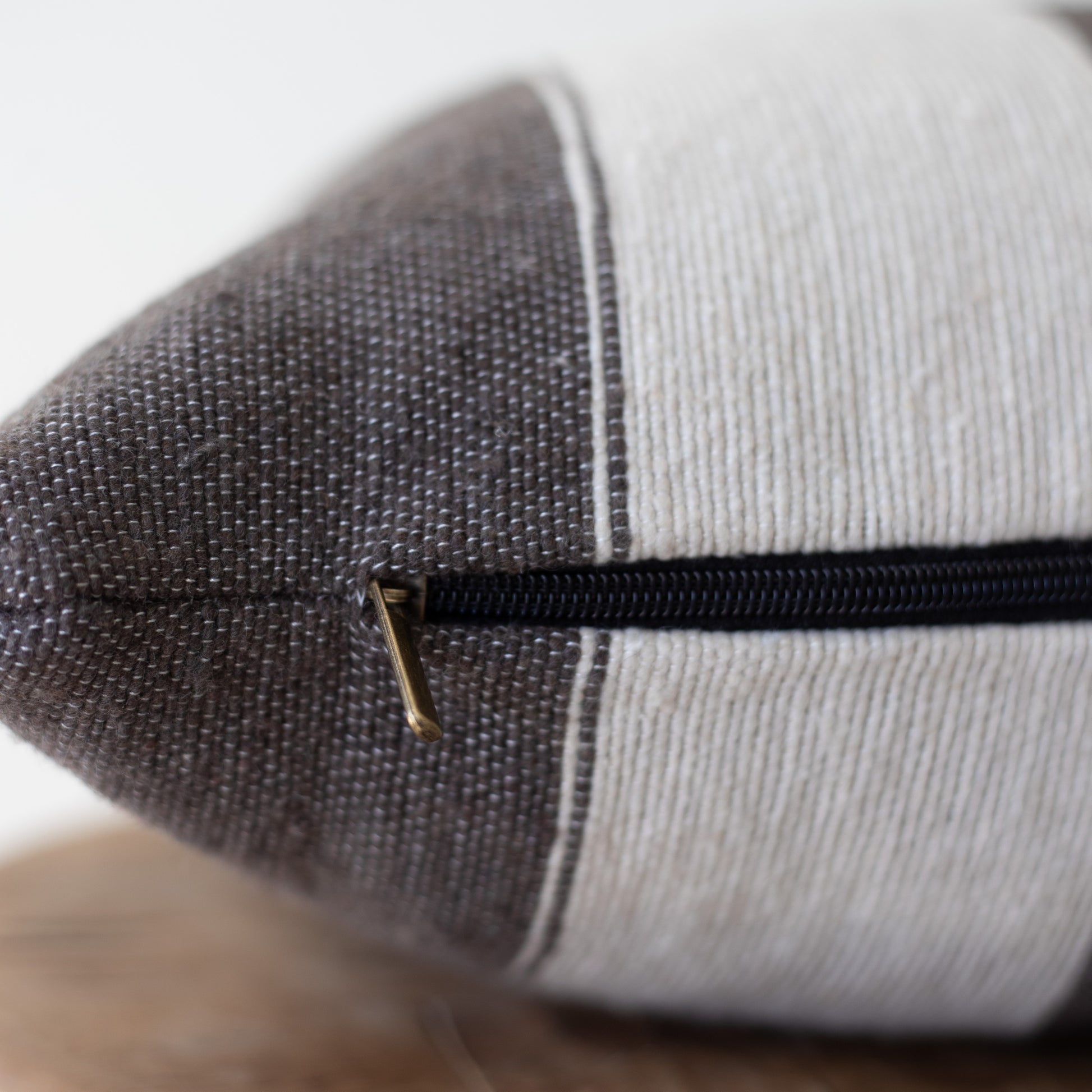 Cylindrical lumbar pillow with dark gray textured fabric on one side, light gray ribbed fabric on the other, and black zipper