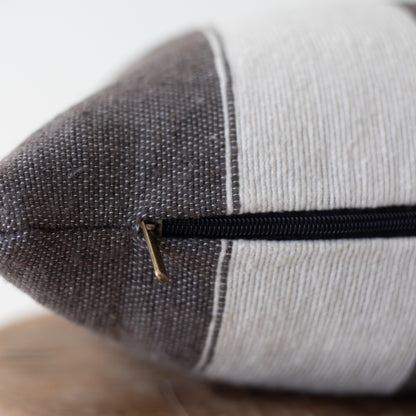 Cylindrical lumbar pillow with dark gray textured fabric on one side, light gray ribbed fabric on the other, and black zipper