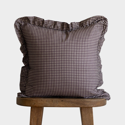 Plum and white gingham square pillow with ruffled edges on wooden stool.