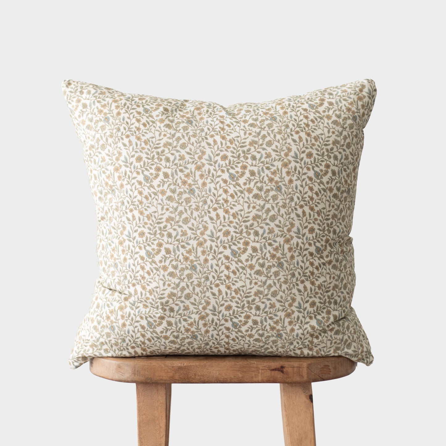 Beige and white leaf-patterned throw pillow displayed on wooden chair.