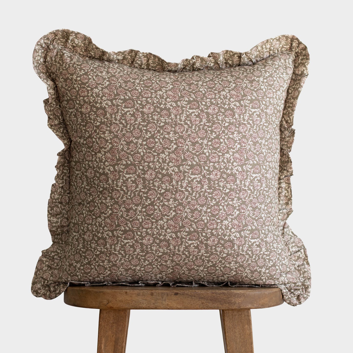 Beige and cream floral patterned square pillow with ruffled edges on all four sides.