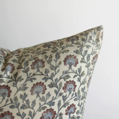 Cream pillow with multicolor floral botanical print featuring red and blue flowers and green leaves throughout.