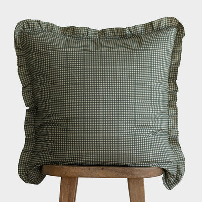 Green and white gingham pillow cover with ruffled edges displayed on wooden stool.