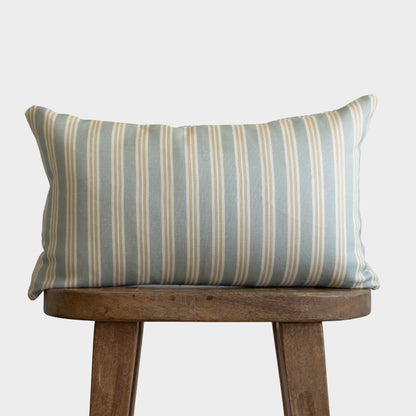 Rectangular pillow with vertical stripes in gray, beige, and cream on wooden stool.