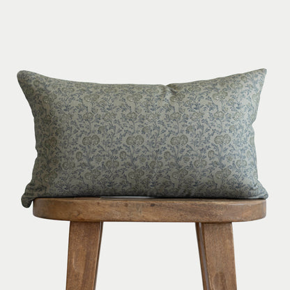 Green damask patterned lumbar pillow displayed on wooden stool.