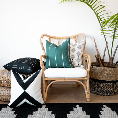 Four outdoor pillow covers in teal striped, cream geometric, black striped, and black-white geometric patterns displayed on r