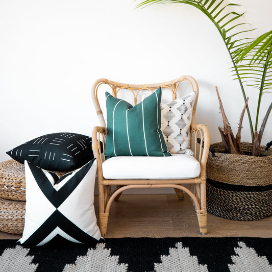 Four outdoor pillow covers in teal striped, cream geometric, black striped, and black-white geometric patterns displayed on r