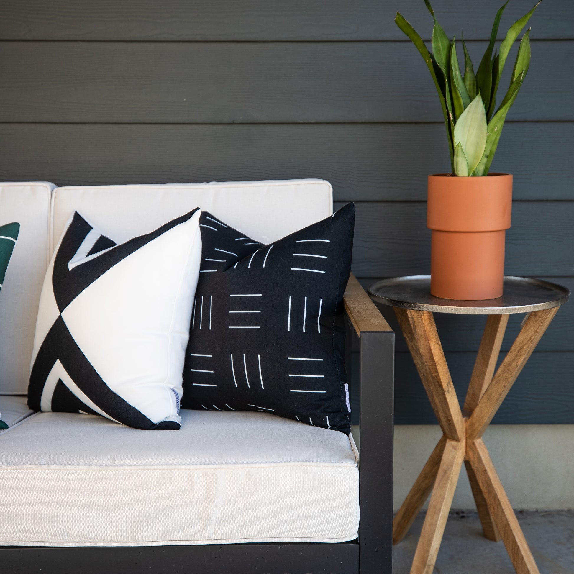 Two black and white geometric patterned outdoor pillow covers displayed on a white outdoor sofa.