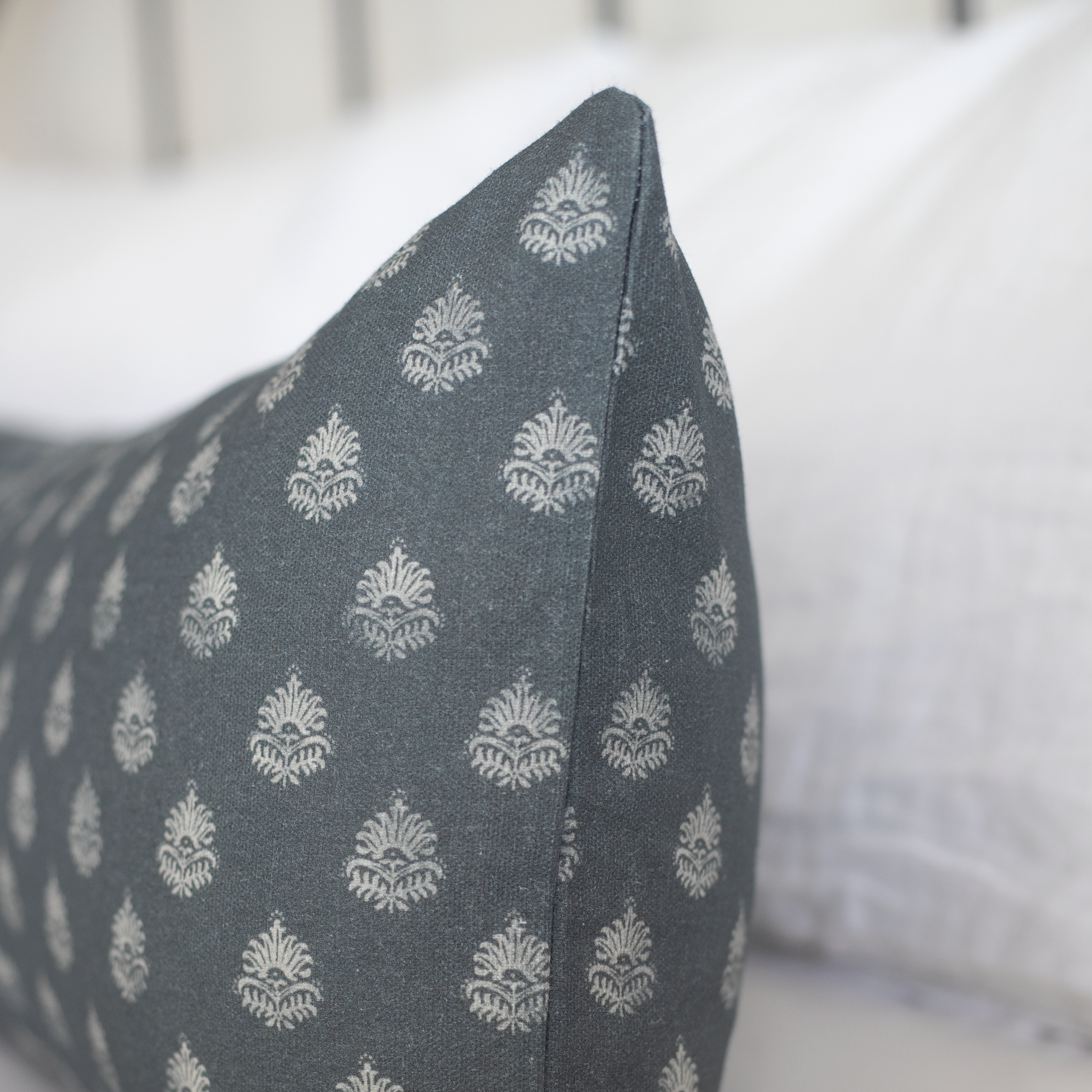 Blue-gray lumbar pillow with repeating cream damask floral motif pattern.