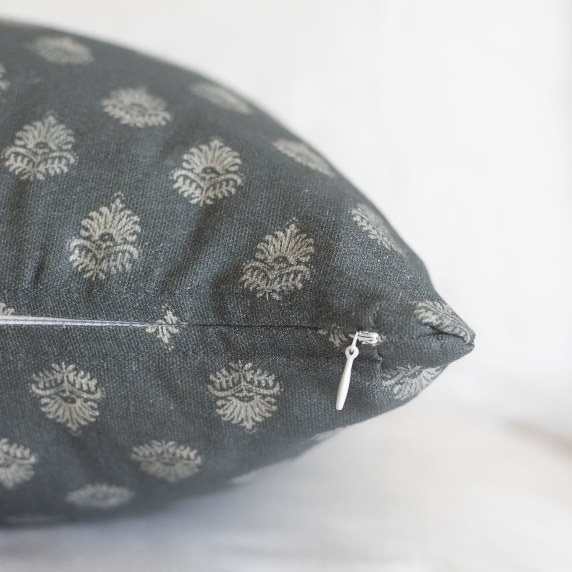Blue-gray lumbar pillow with cream damask pattern and white zipper closure.