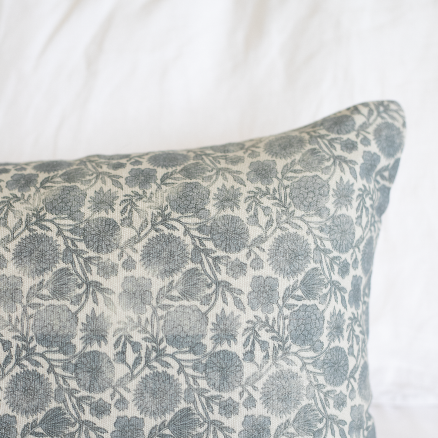 Blue and cream lumbar pillow with floral botanical print featuring rounded flowers and leafy stems throughout.