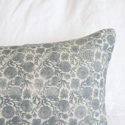 Blue and cream lumbar pillow with floral botanical print featuring rounded flowers and leafy stems throughout.